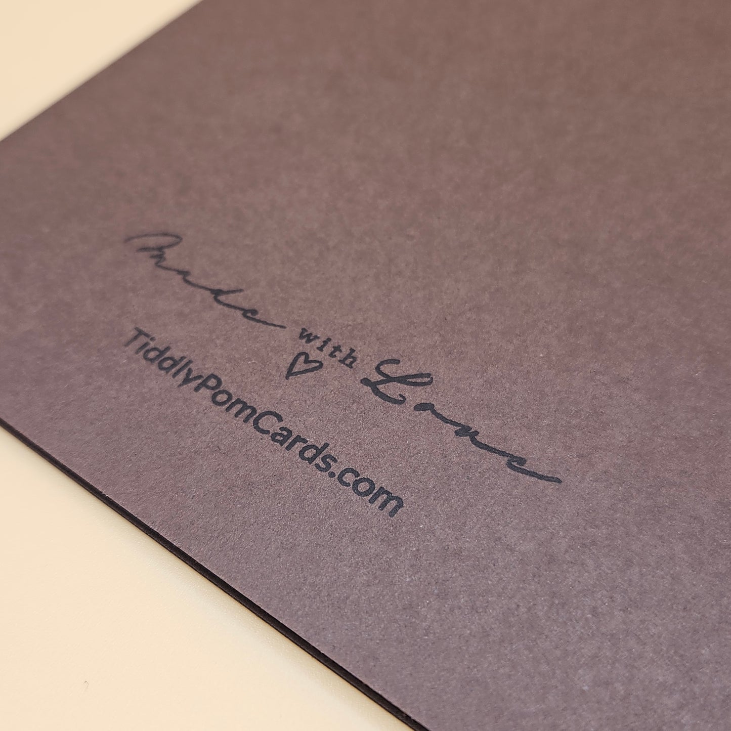 Brown card with 'Made with Love' and a website URL on a beige background