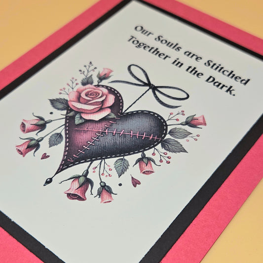 Card with heart design, roses, and text 'Our Souls are Stitched Together in the Dark' on a pink border.