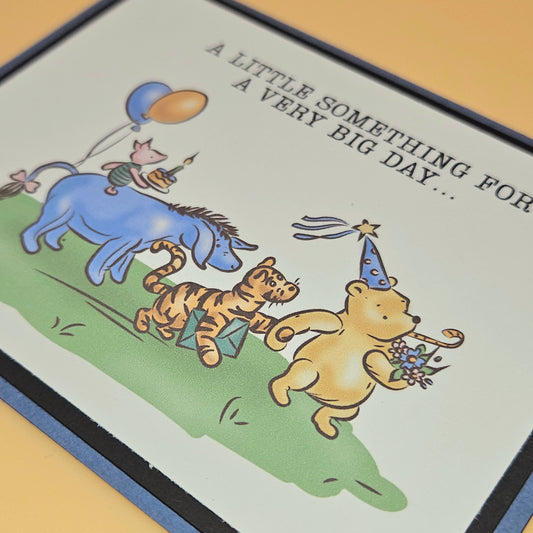Cartoon card with Pooh and friends celebrating a birthday, featuring text 'A little something for a very big day'.