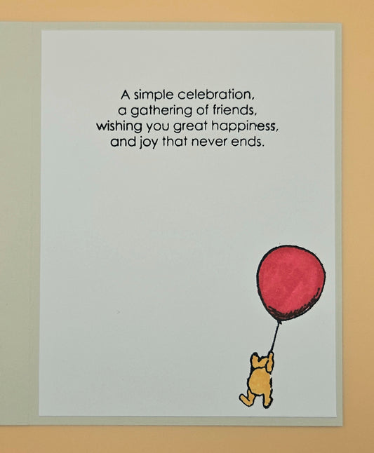 Card with Winnie the Pooh holding a red balloon and text on a beige background