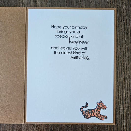 Greeting card with a tiger illustration and birthday message on a wooden surface