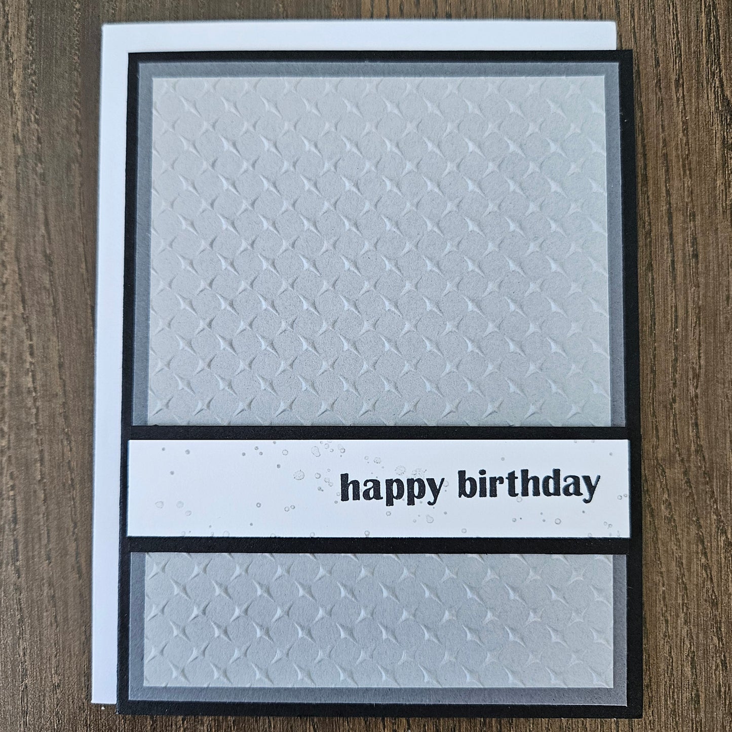 Handmade birthday card with embossed silver grey diamond pattern and bold lowercase happy birthday sentiment banner on black border.