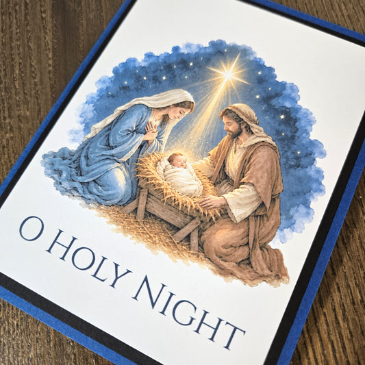 Angled close-up of printed Holy Family nativity illustration and blue starry sky on O Holy Night card