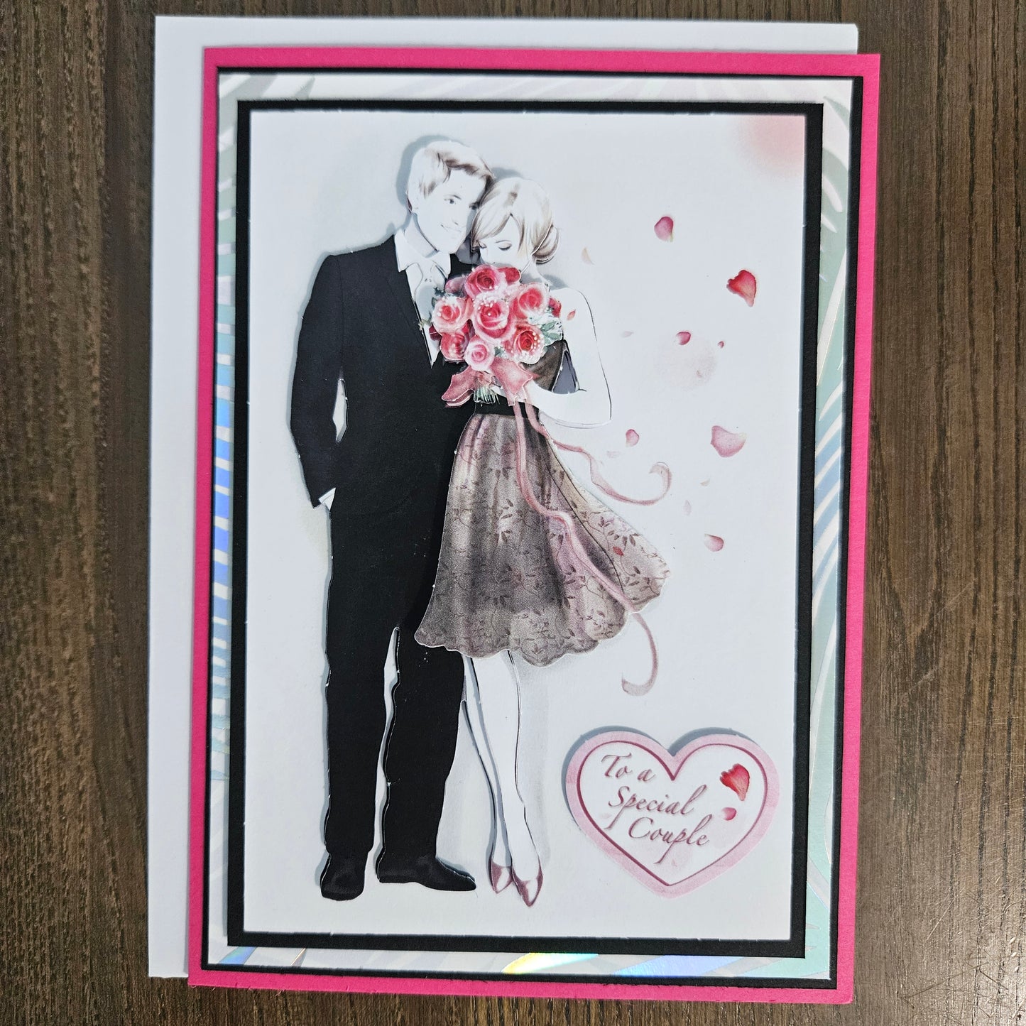 Greeting card with wedding dress, bouquet, and heart-shaped message on a wooden surface