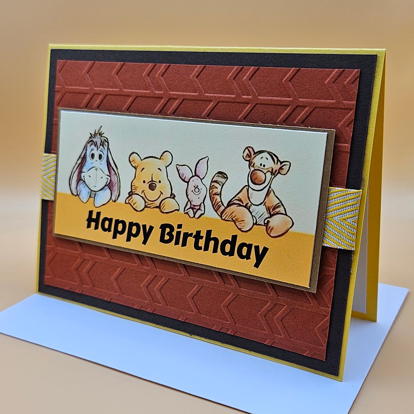 Birthday card with cartoon characters and 'Happy Birthday' text on a brown and yellow background.