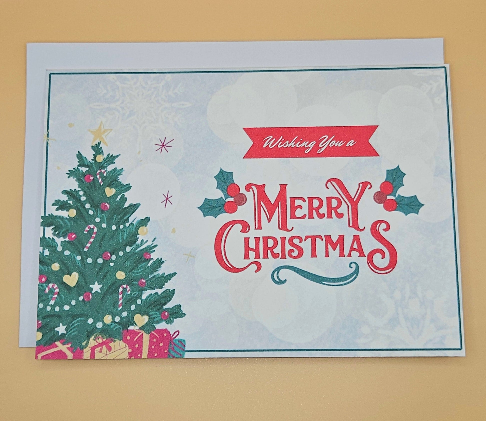 Christmas card with a tree, presents, and 'Merry Christmas' text on a beige background