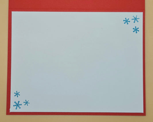 White card with blue snowflakes on a red border against a beige background