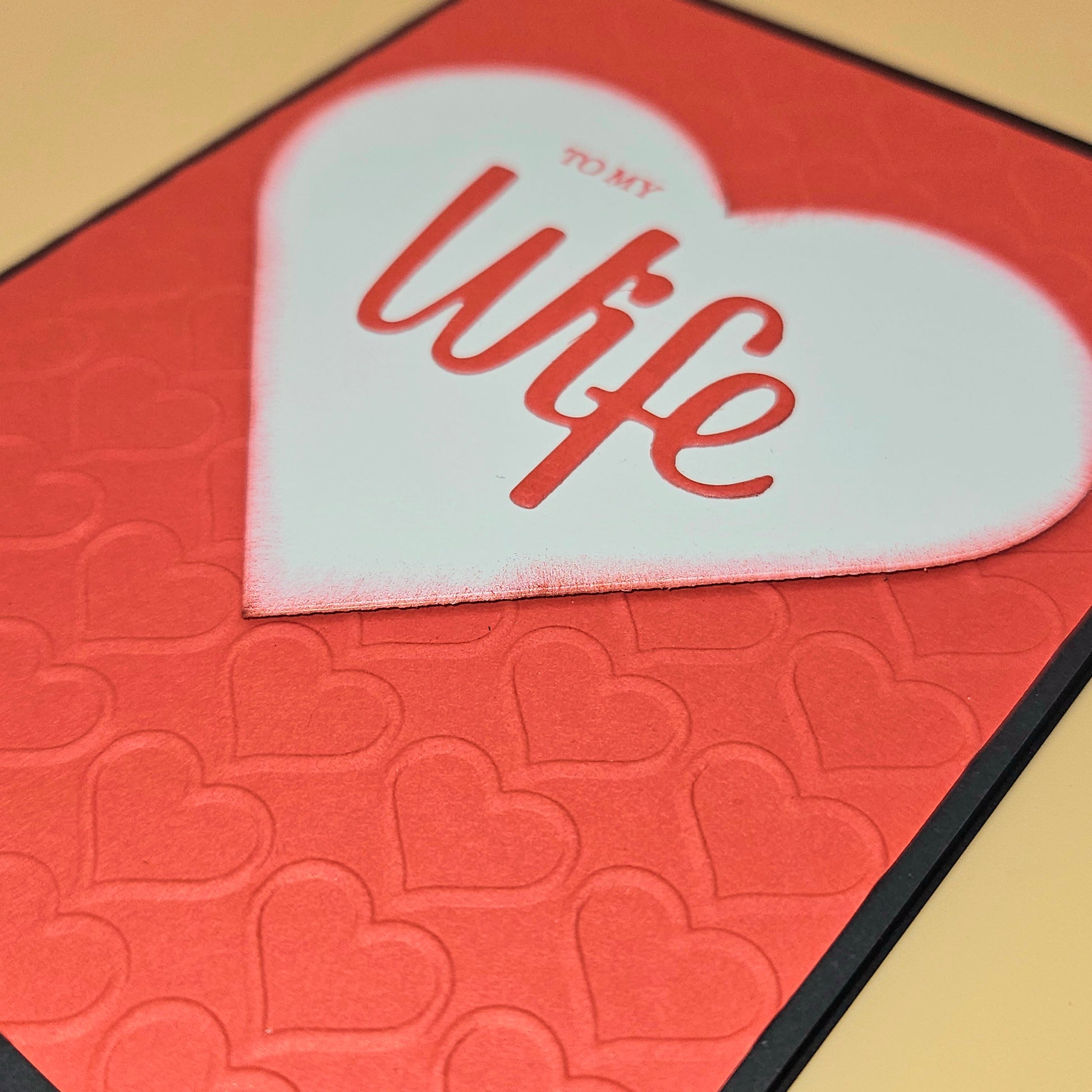 Heart-shaped card with 'To My Wife' text on a red background with heart patterns.