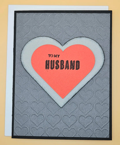 Card with a pink heart and 'To my Husband' text on a gray background with heart patterns