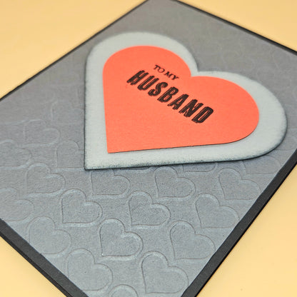 Heart-shaped card with 'To My Husband' text on a textured heart-patterned card