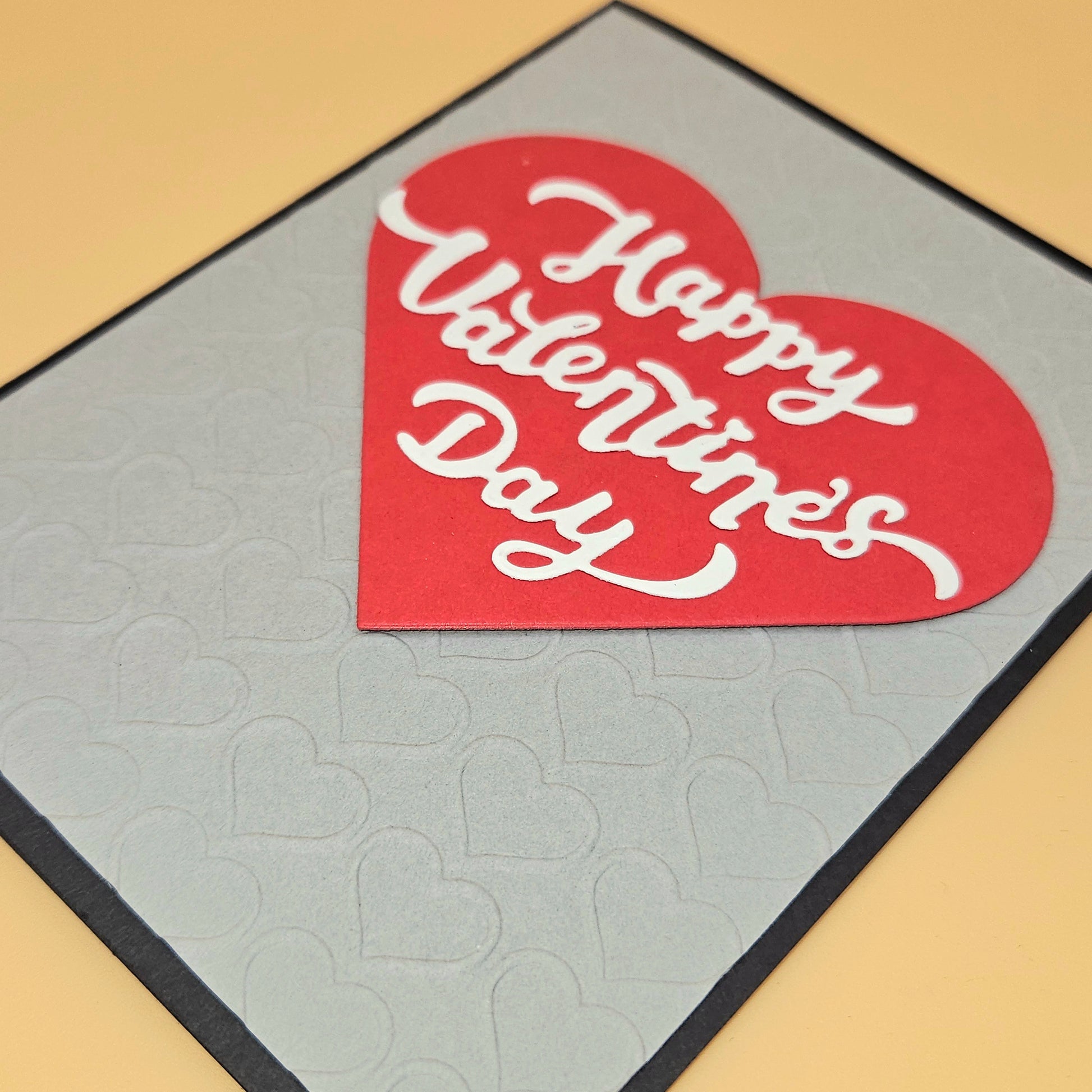 Heart-shaped 'Happy Valentine's Day' card on a textured surface