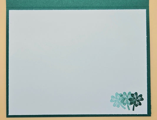 Note card with a green border and a small floral design in the corner on a beige background