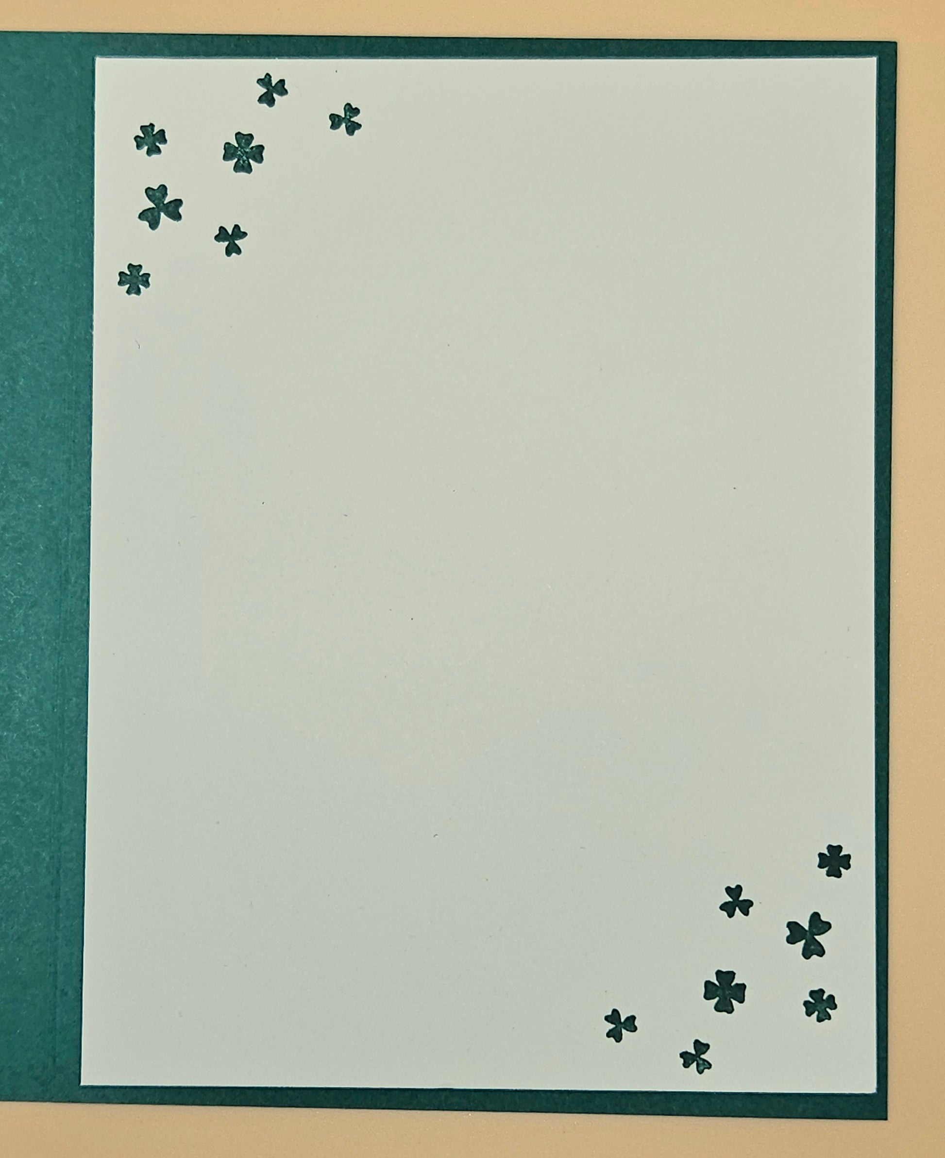 White paper with black four-leaf clover designs on a beige background