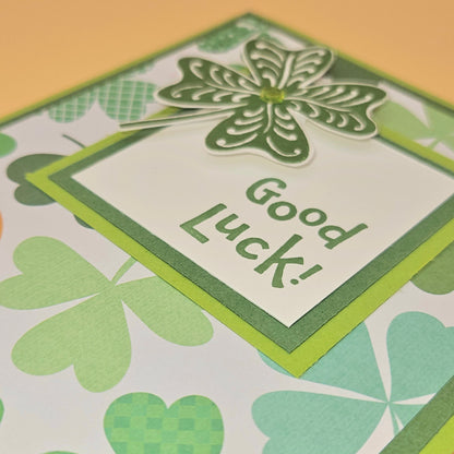 Card with a four-leaf clover and 'Good Luck!' text on a patterned background