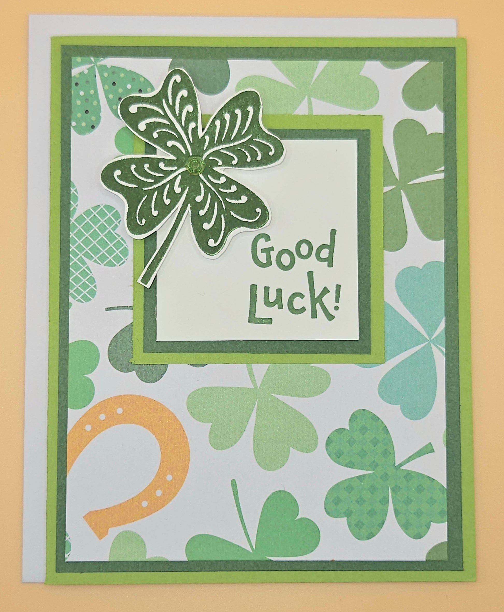 Greeting card with shamrock, horseshoe, and 'Good Luck!' text on a patterned background