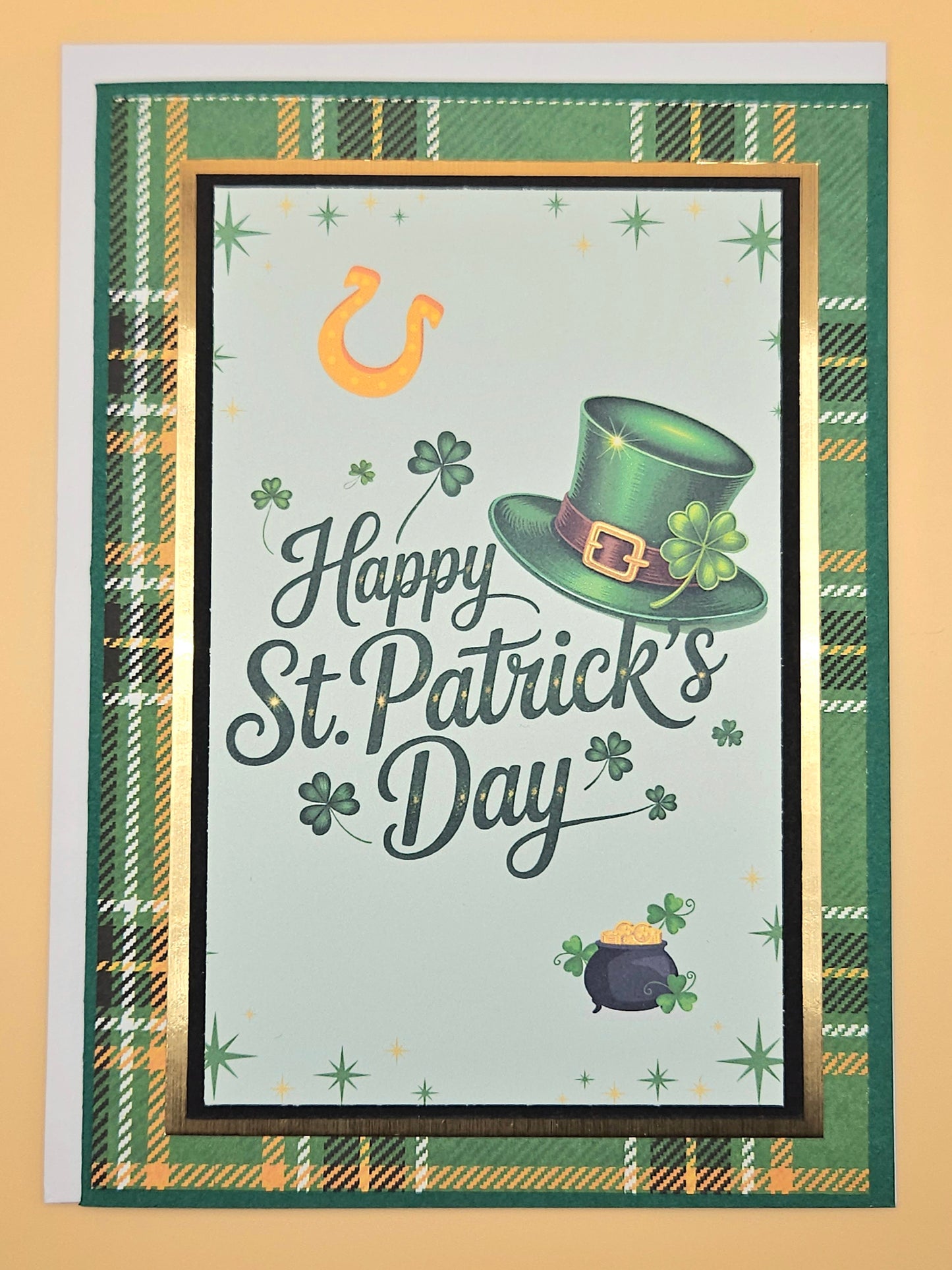 St. Patrick's Day card with green hat, pot of gold, and shamrock on a plaid border.
