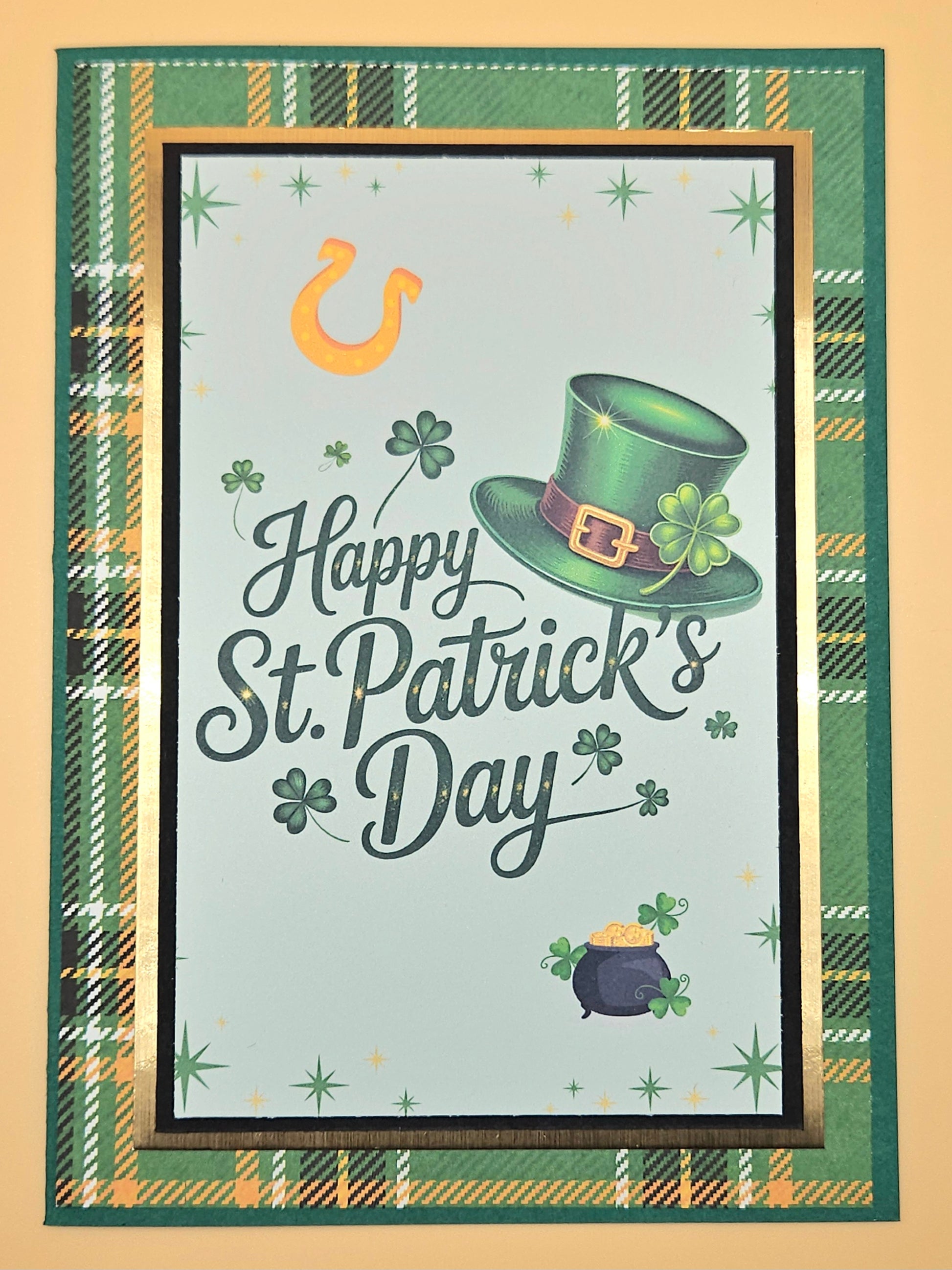 St. Patrick's Day card with green hat, pot of gold, and shamrock on a plaid border.