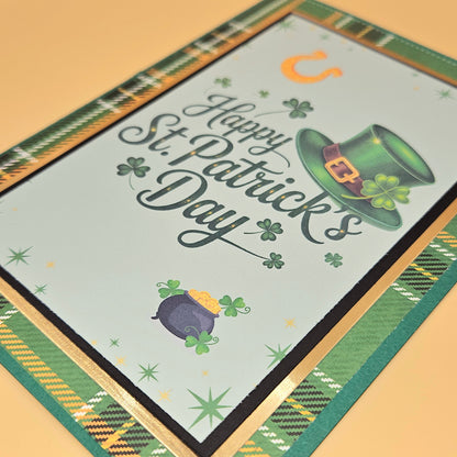 St. Patrick's Day card with green hat, pot of gold, and shamrocks on a checkered border.