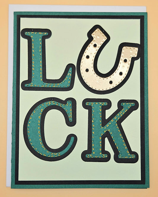 Card with 'LUCK' text in a decorative font on a light green background