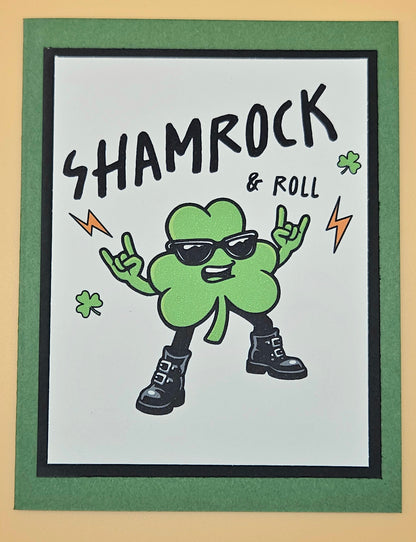 Cartoon shamrock character with sunglasses and boots, text 'SHAMROCK & ROLL' on a white background.