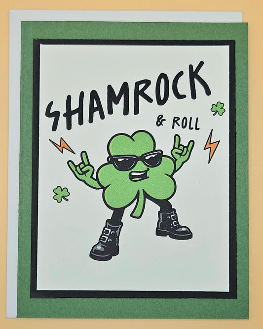 Card with a cartoon shamrock wearing sunglasses and boots, text 'SHAMROCK & ROLL', on a green border.