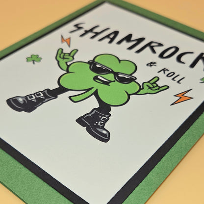 Card with a green clover character dancing and text 'Shamrock & Roll' on a beige background