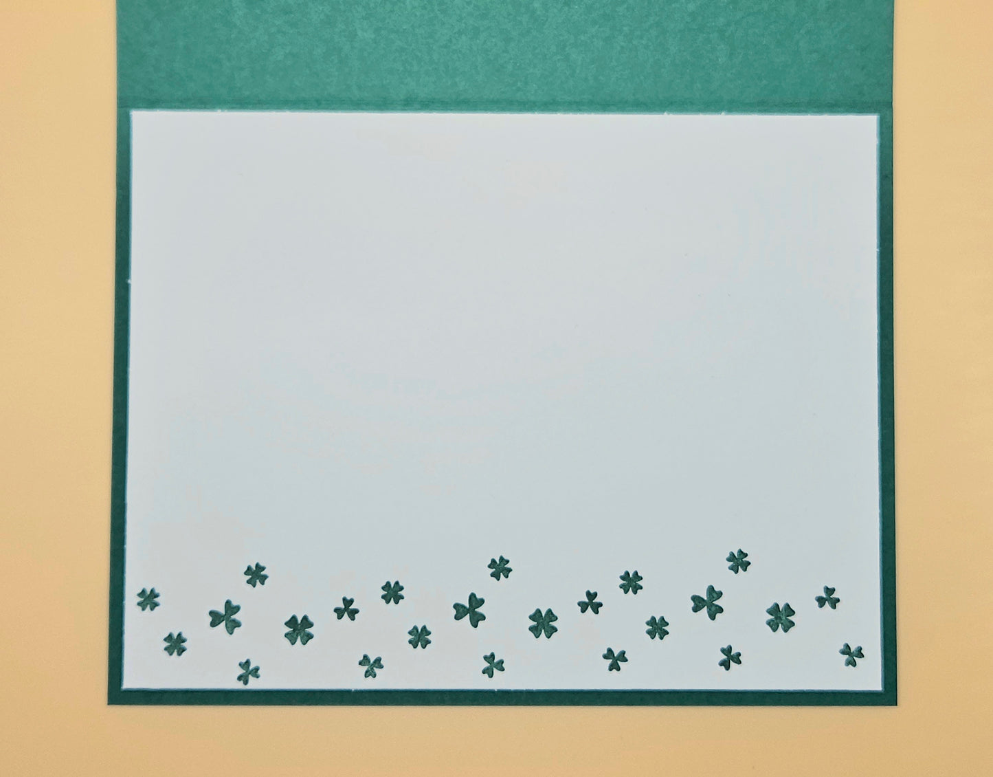 Green border with small clover patterns on a beige background