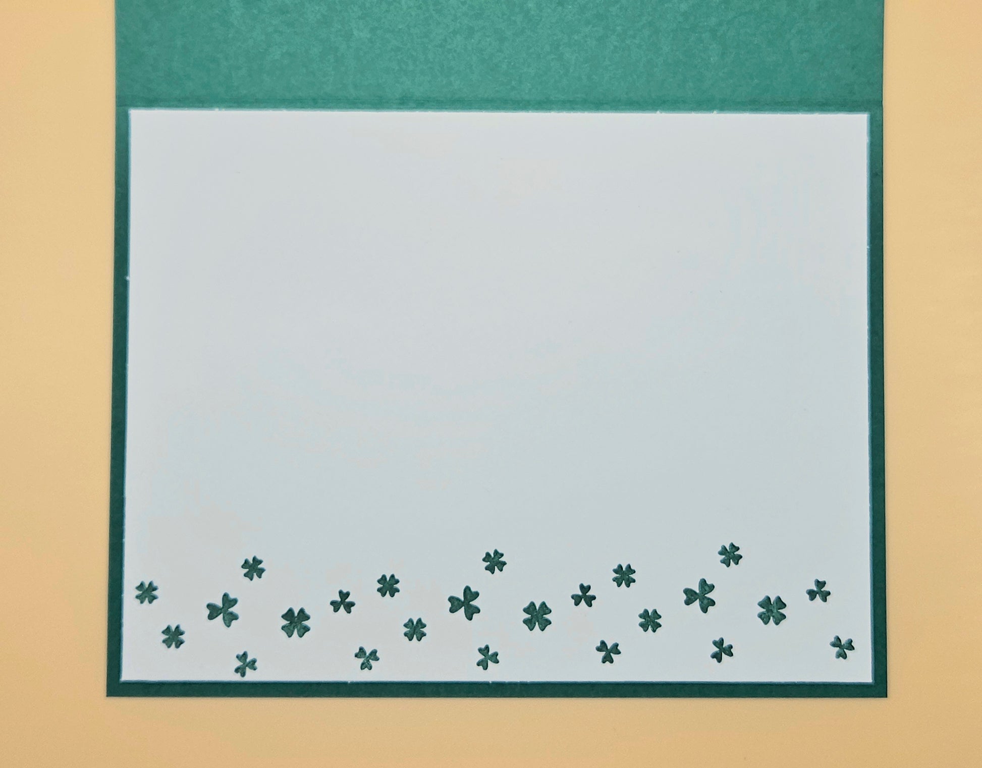 Green border with small clover patterns on a beige background