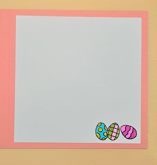 Colorful Easter eggs on a white card with a pink border against a beige background