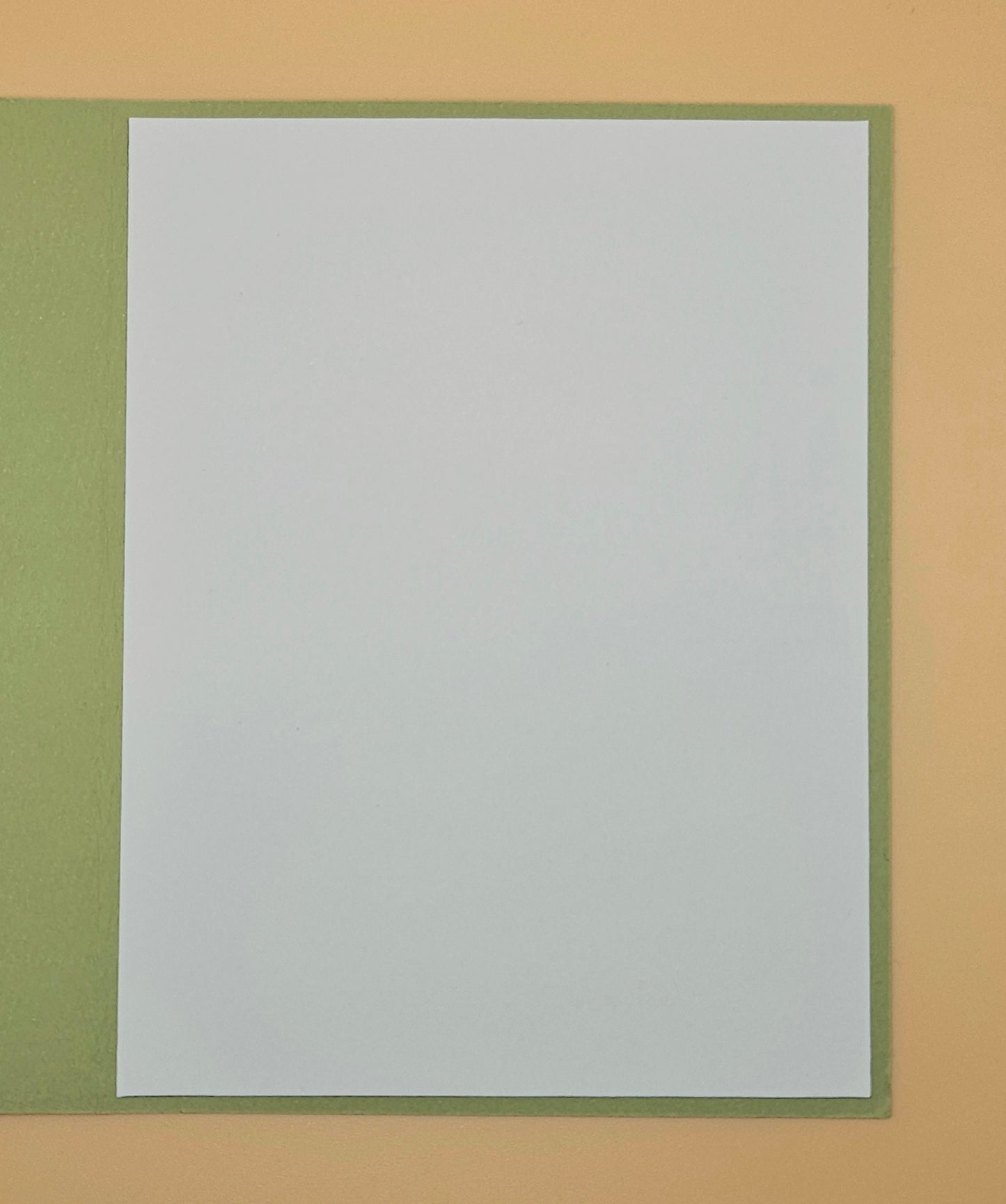 White sheet of paper with green border on a beige background