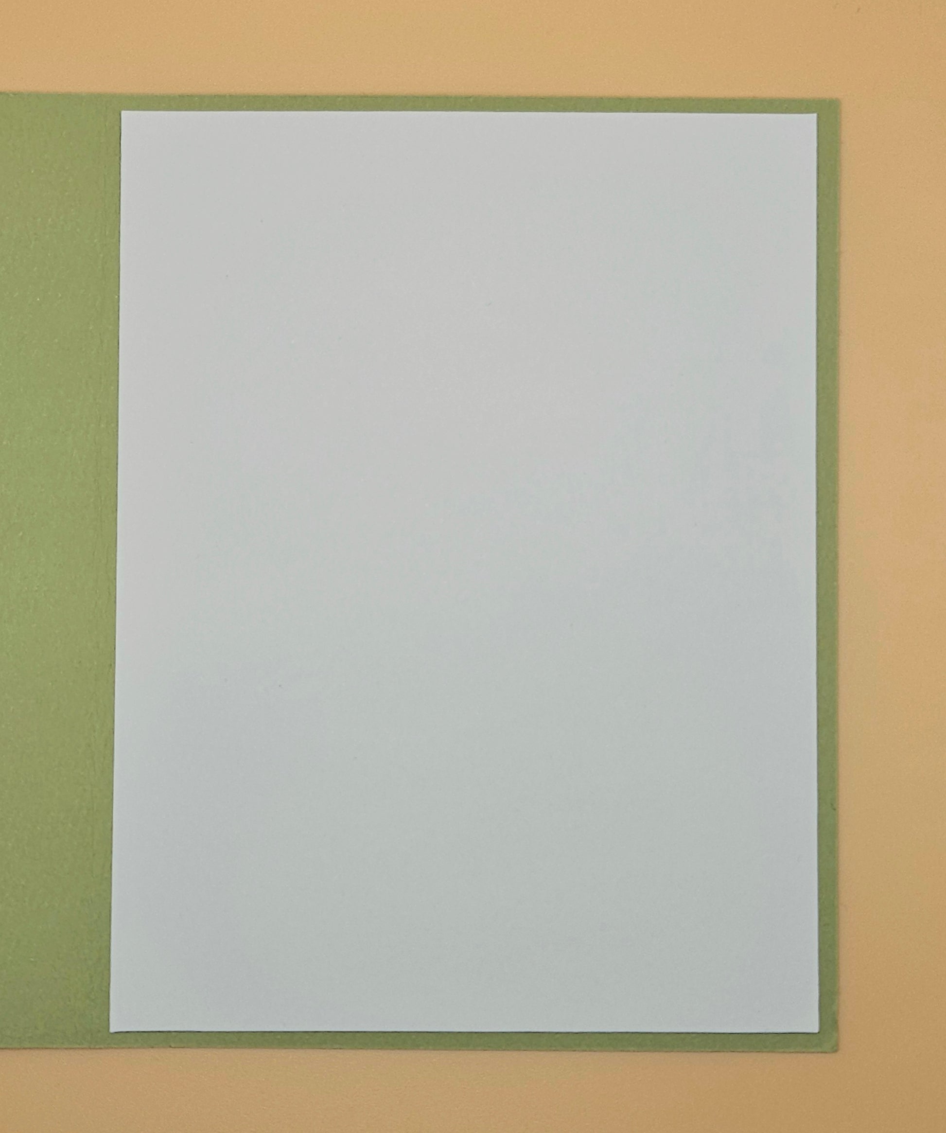 White sheet of paper with green border on a beige background