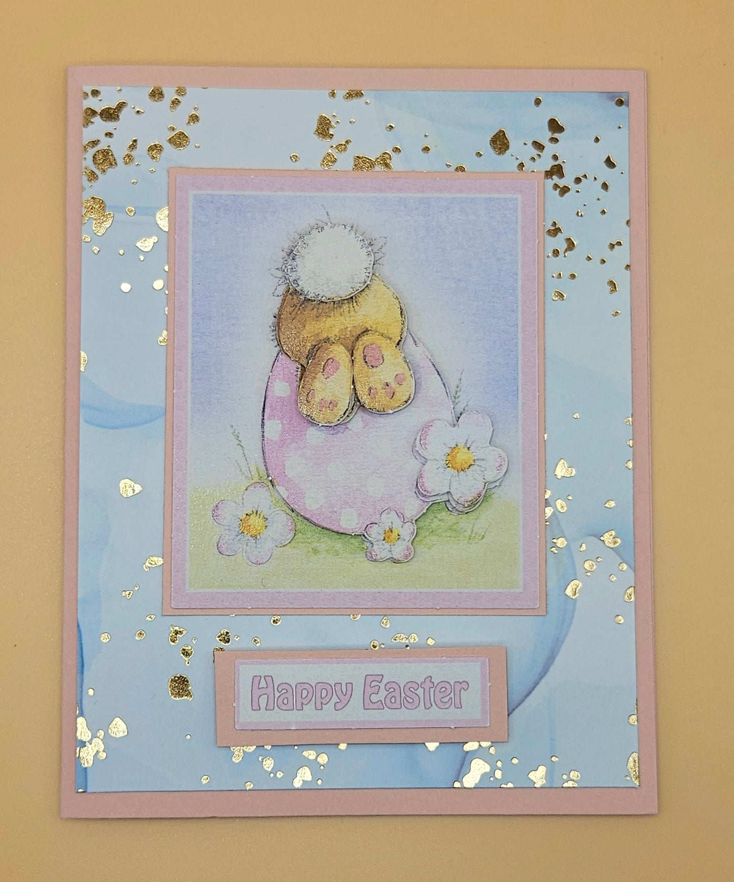 Easter card with a bunny in an egg, flowers, and 'Happy Easter' text on a blue background.