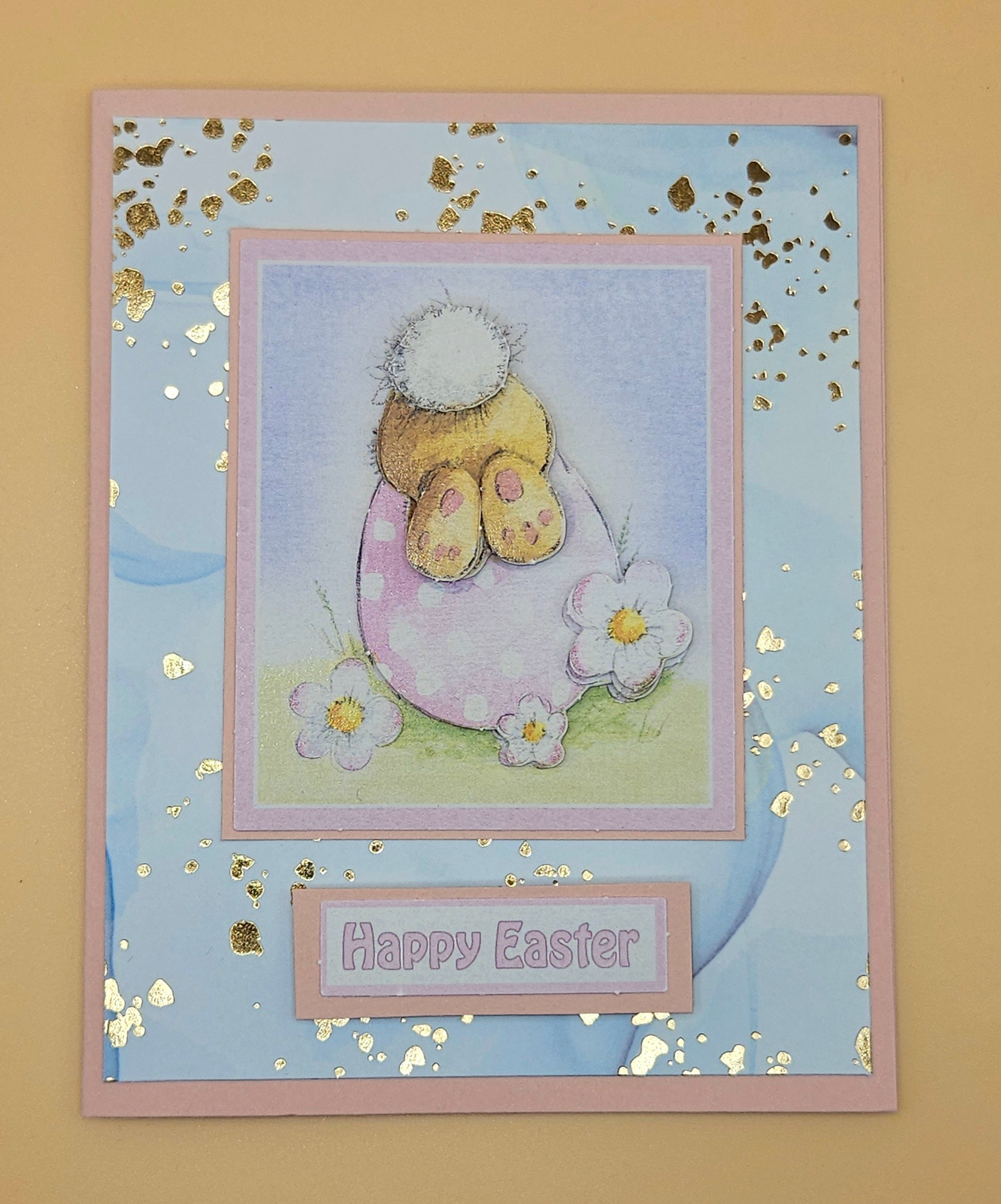 Easter card with a bunny in an egg, flowers, and 'Happy Easter' text on a blue background.