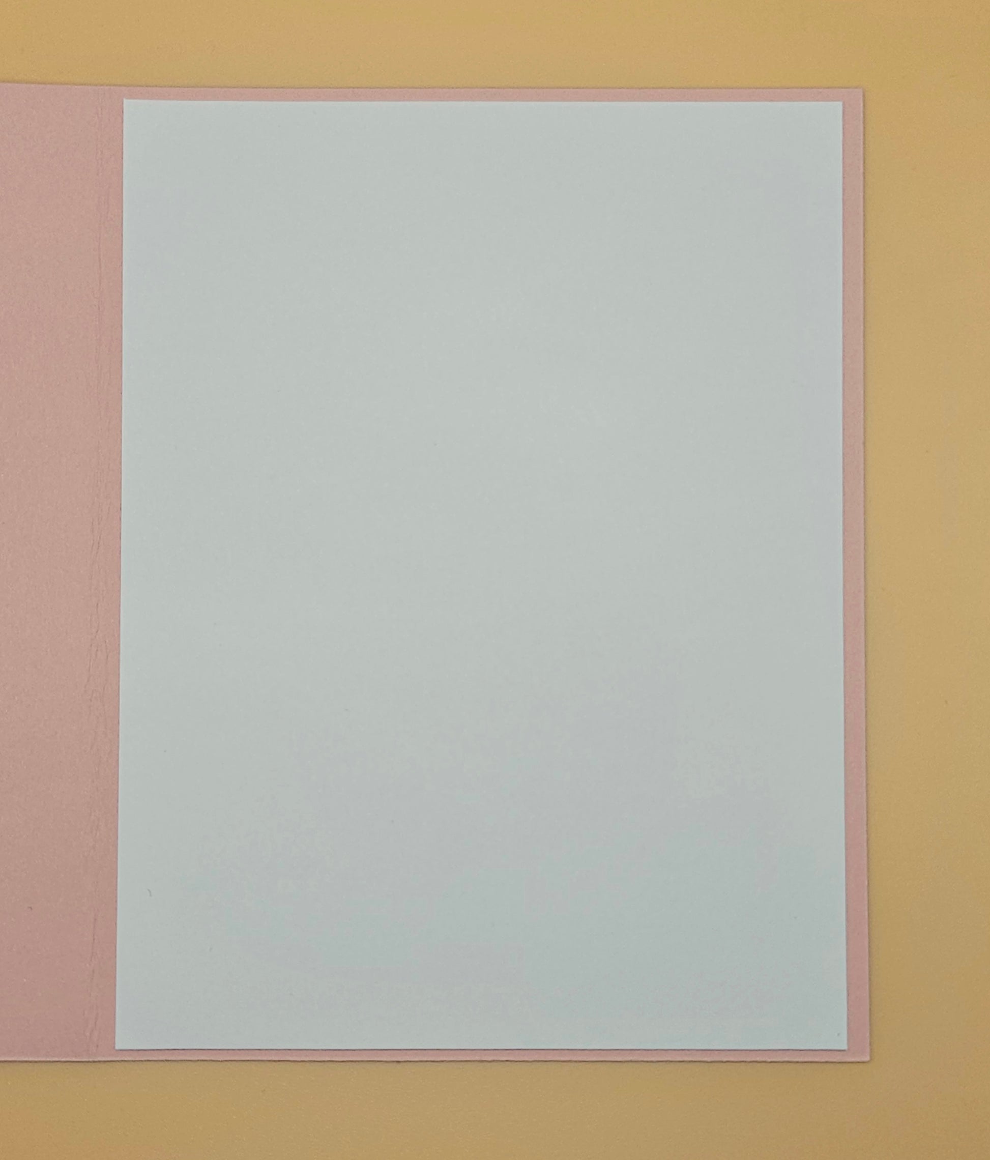 White sheet of paper with pink border on a yellow background