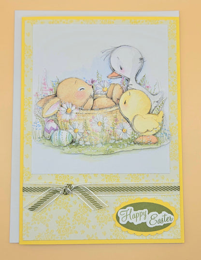Easter card with teddy bear, ducklings, and basket of eggs on a yellow background