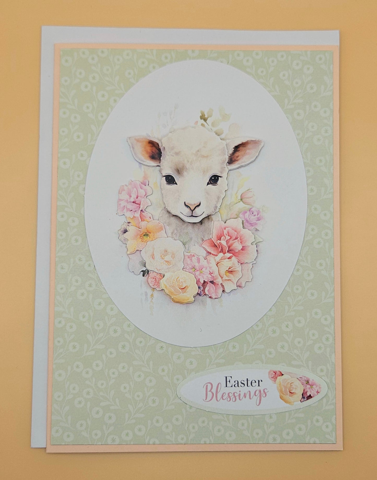 Greeting card with a lamb illustration and floral wreath on a patterned background