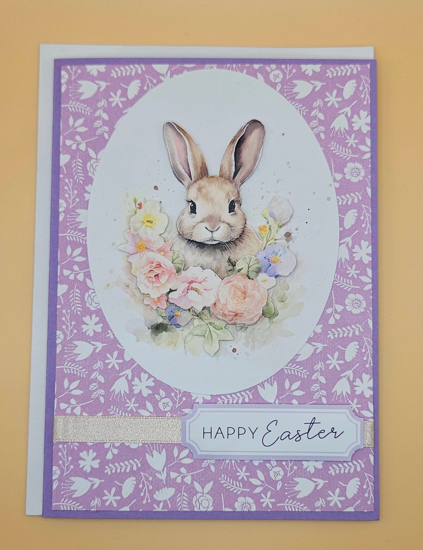 Easter card with a bunny and flowers on a purple patterned background
