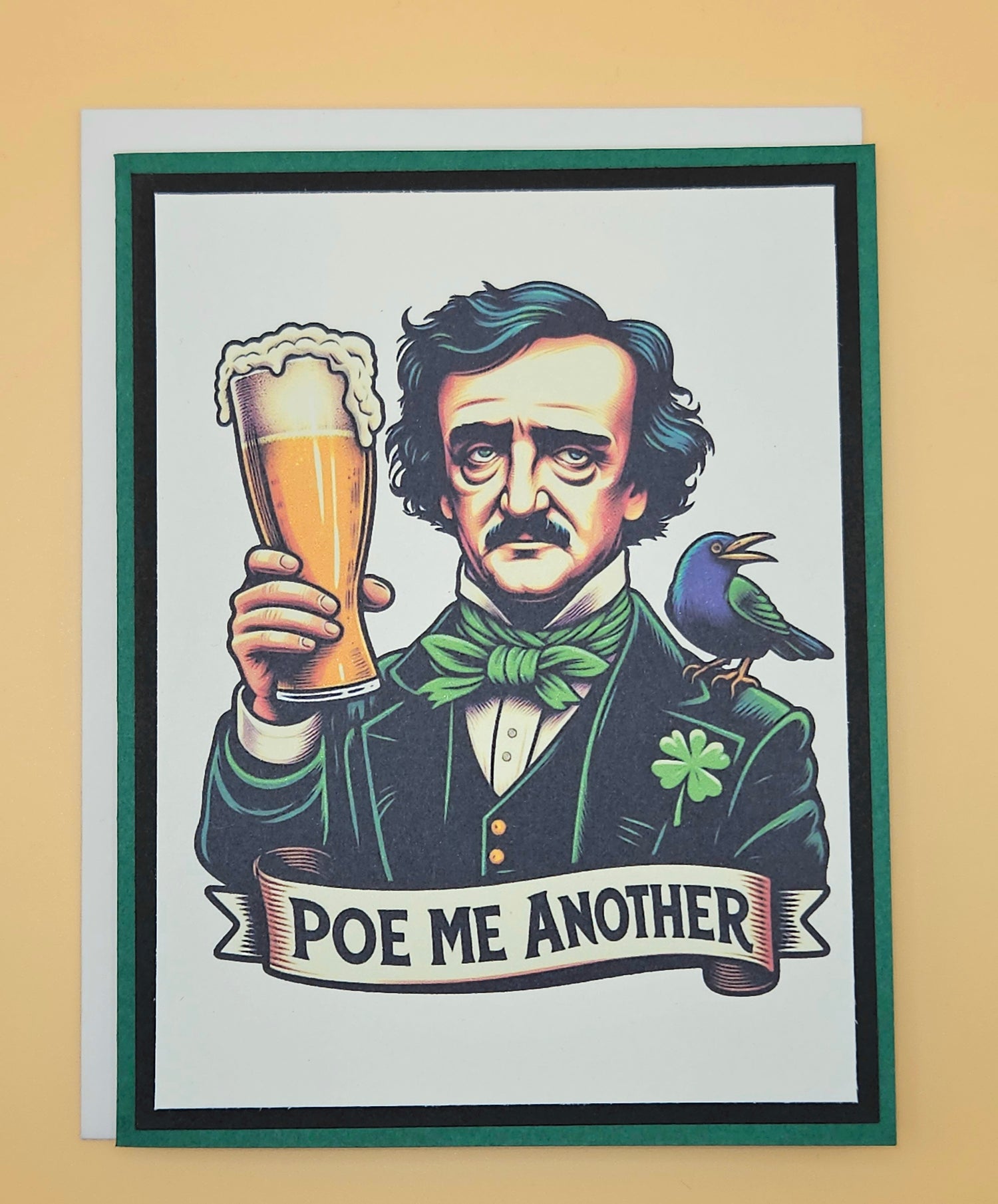 Handmade funny gothic card featuring an illustration of Edgar Allan Poe raising a frothy pint of beer with a raven on his shoulder and a small shamrock on his lapel, framed by a bold green cardstock border.