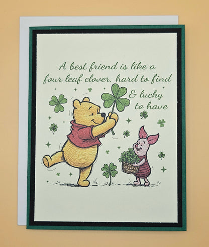 Card with Winnie the Pooh and Piglet holding four-leaf clovers on a beige background