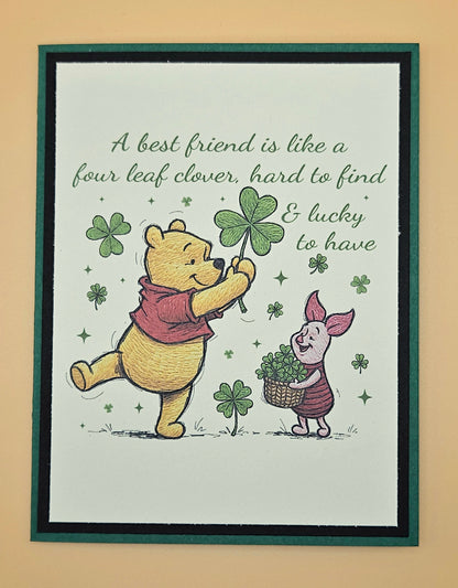 Framed print with Winnie the Pooh and Piglet holding four-leaf clovers and text on a beige background.
