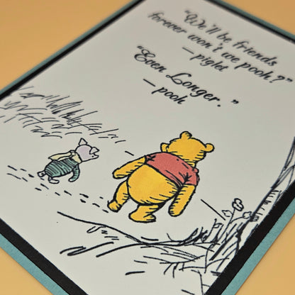 Cartoon illustration of Winnie the Pooh and Piglet with text on a card.