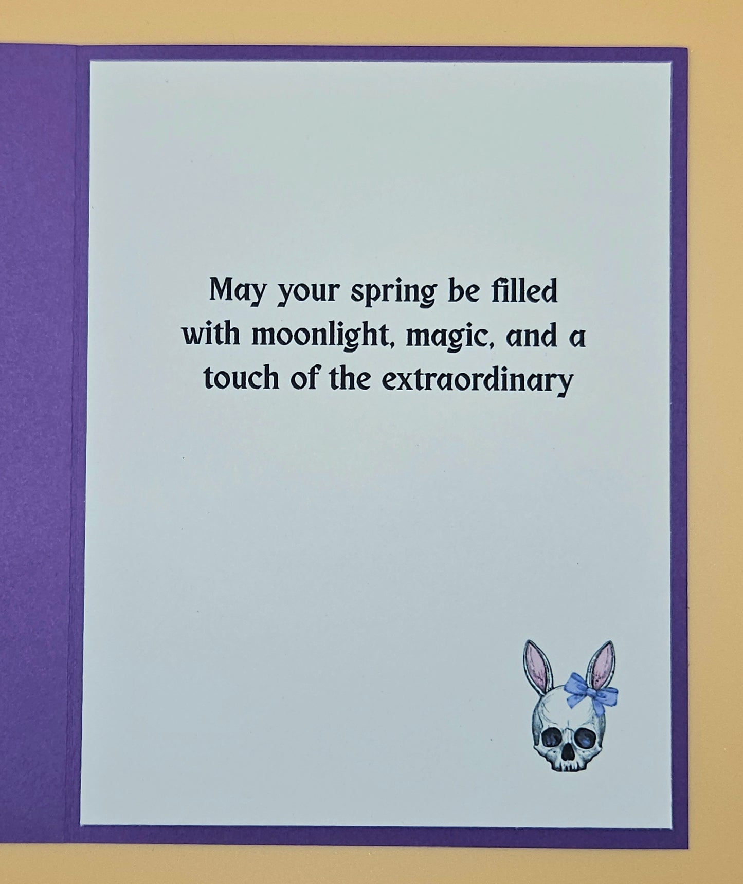 Greeting card with text 'May your spring be filled with moonlight, magic, and a touch of the extraordinary' and a skull with a bow design.