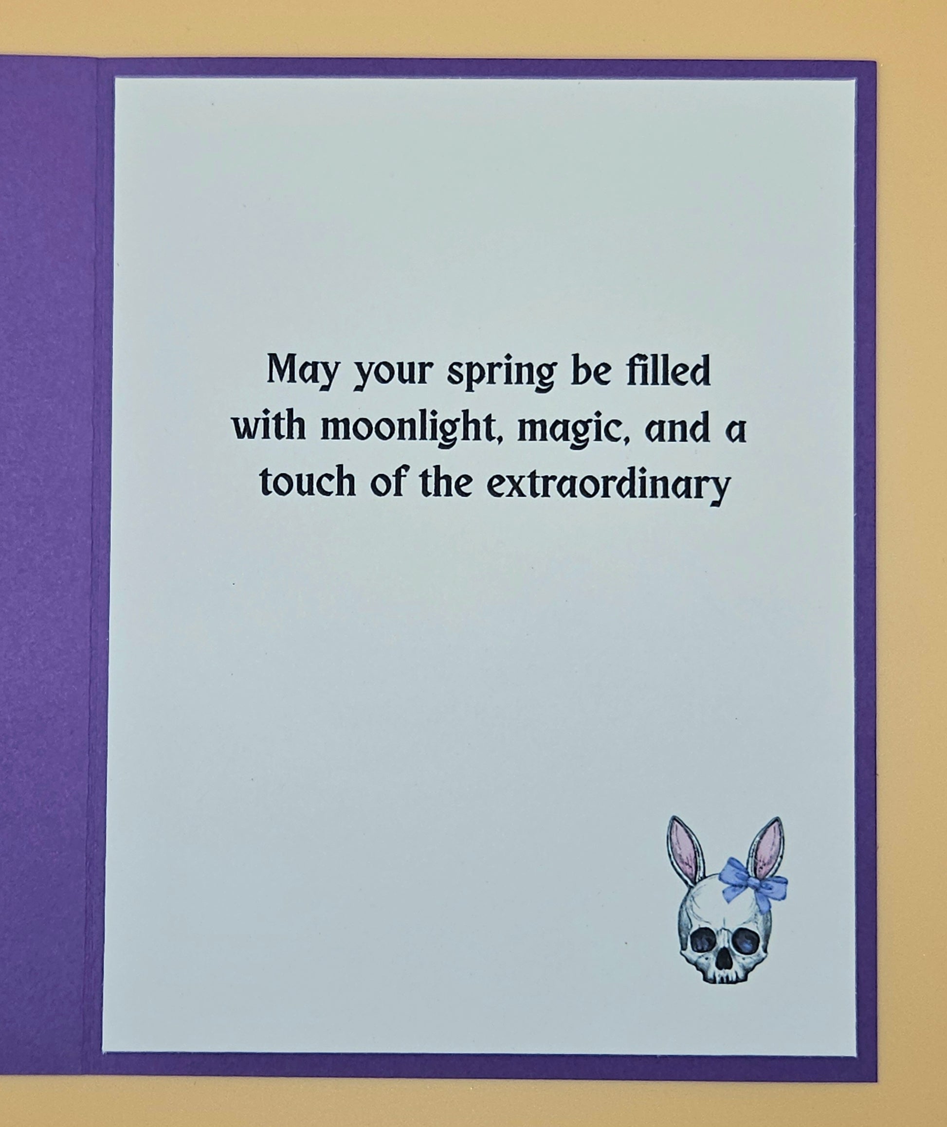 Greeting card with text 'May your spring be filled with moonlight, magic, and a touch of the extraordinary' and a skull with a bow design.