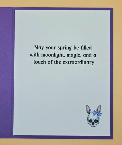 Greeting card with text 'May your spring be filled with moonlight, magic, and a touch of the extraordinary' and a skull with a bow design.