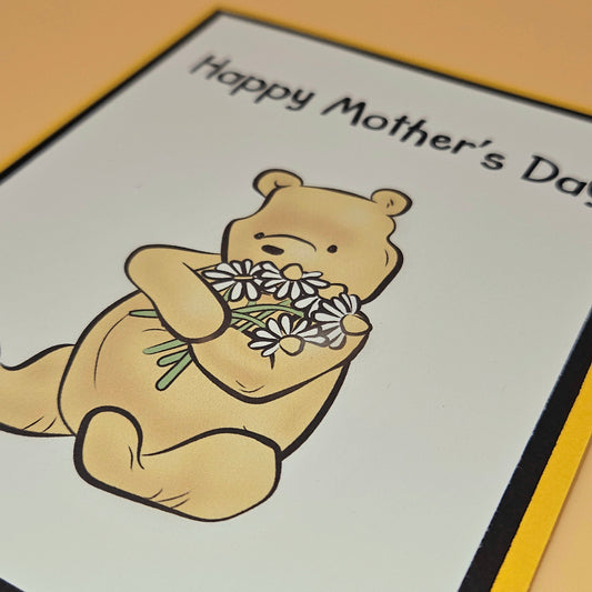Cartoon bear holding flowers with 'Happy Mother's Day' text on a card.
