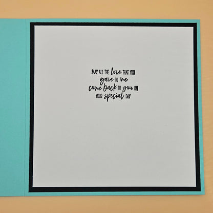 Card with a message on a light gray background with a black border, placed on a beige surface.