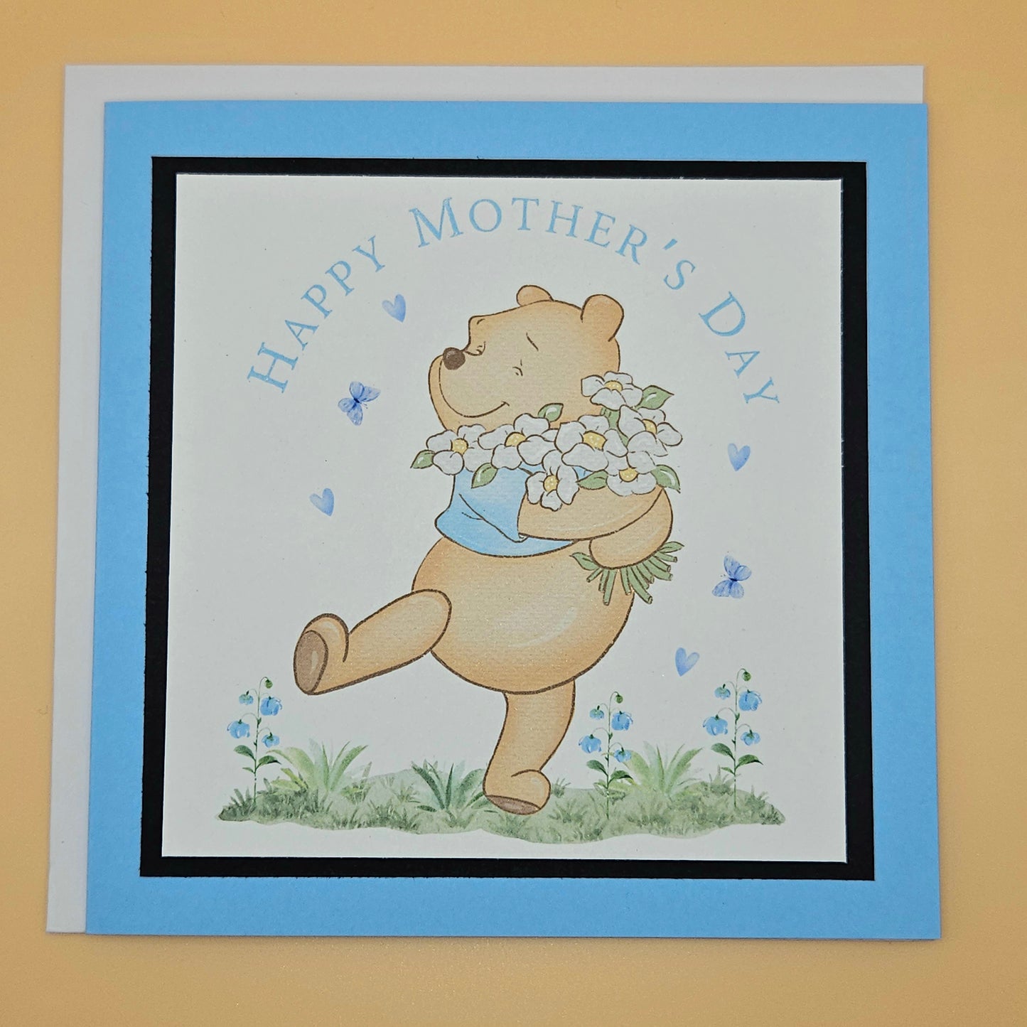 Mother's Day card with a bear holding flowers on a beige background