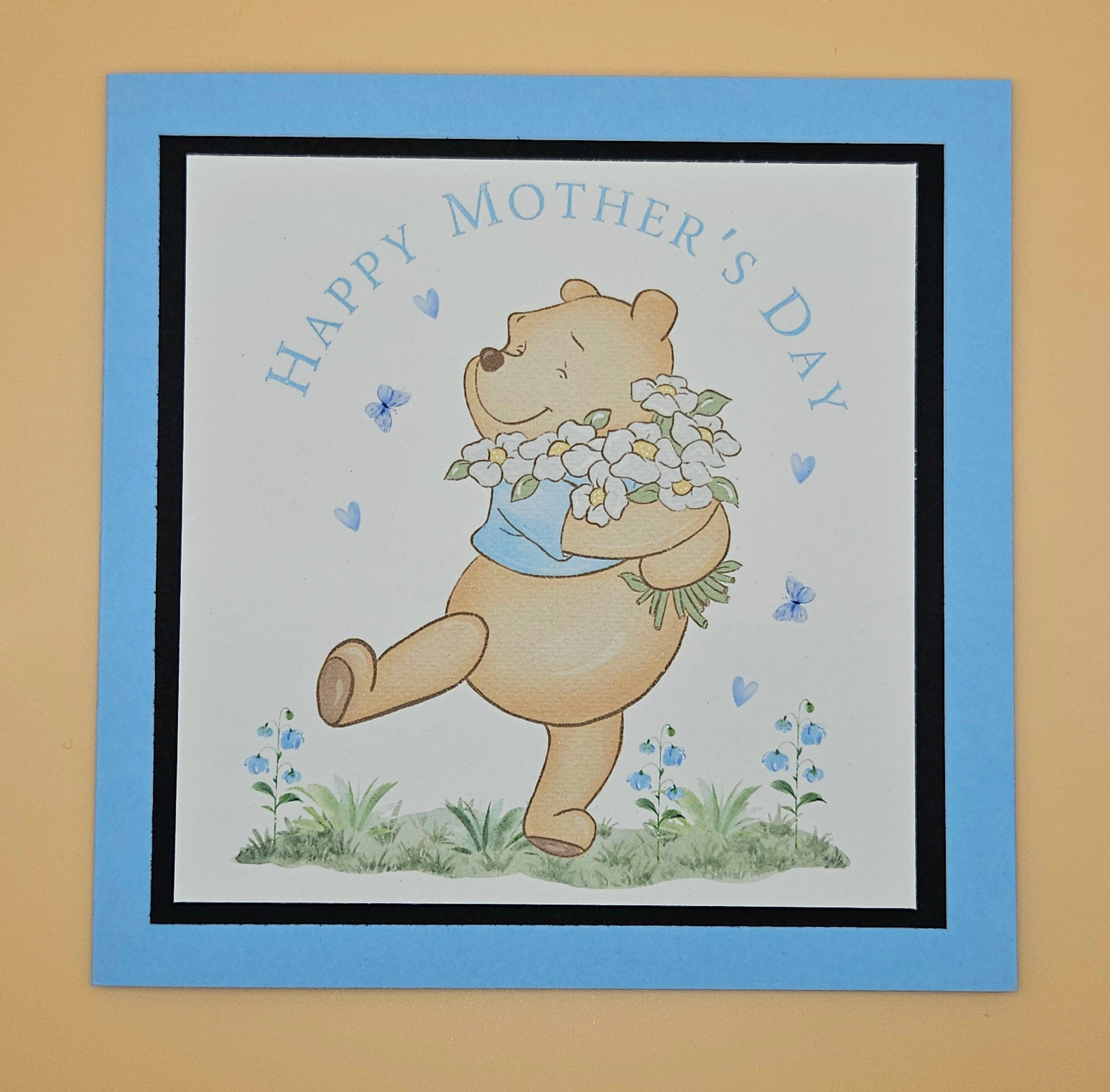 Card with a bear holding flowers and 'Happy Mother's Day' text on a beige background