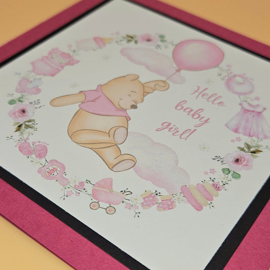 Baby shower card with Winnie the Pooh and floral decorations on a pink background