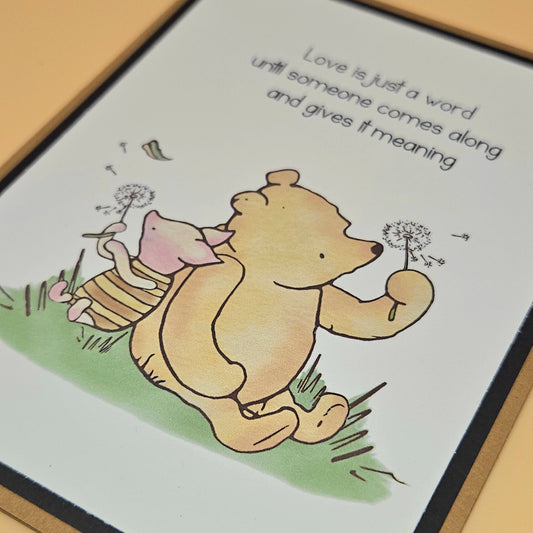 Cartoon bear and piglet holding dandelion seeds with a quote on a card.
